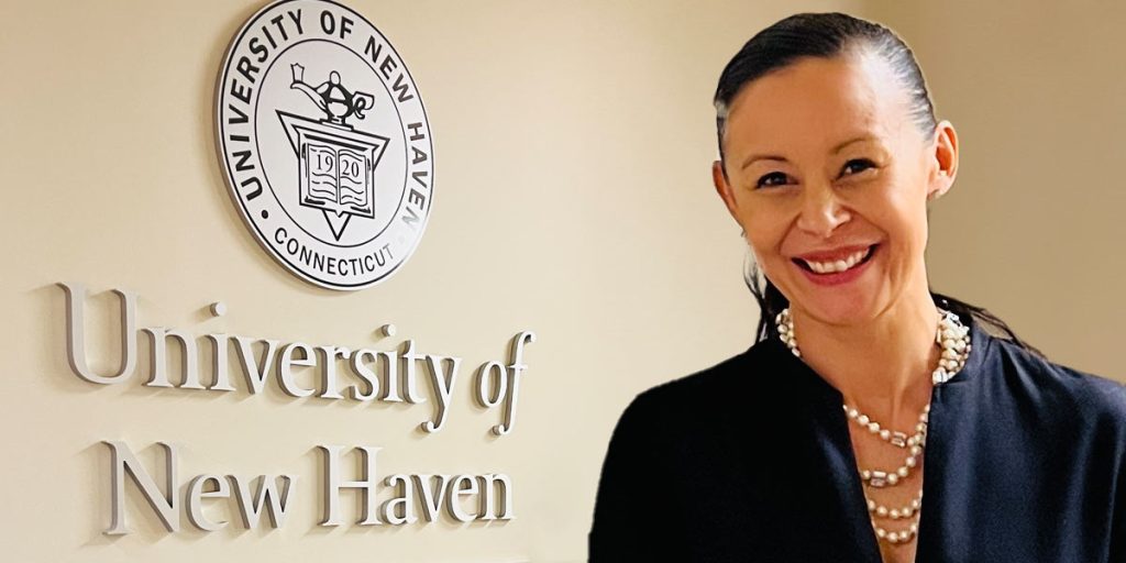 Nikki Hafezi steht vor einem Schild mit der Aufschrift "University of New Haven".